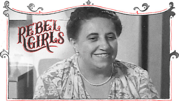 A smiling woman stands in front of a sign that reads 