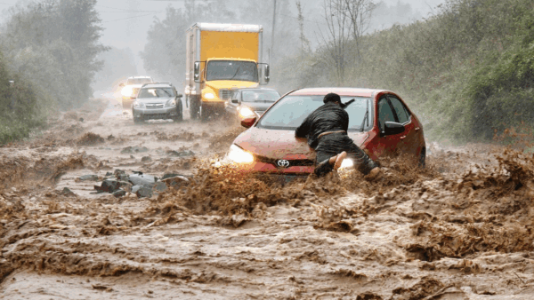 A man holds on to a car during a flash flood