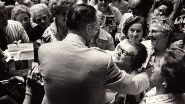 Lawrence Welk hugging a lady in a crowd