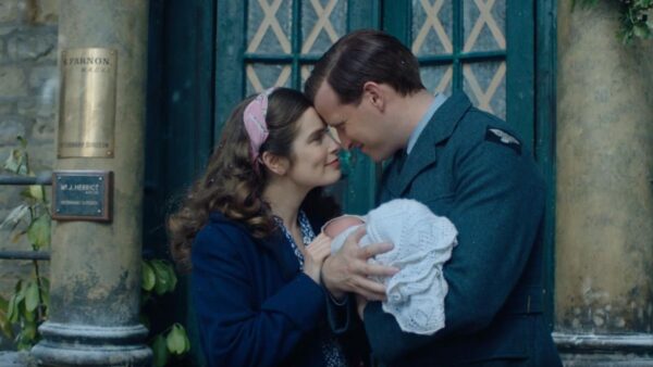 A man and woman holding a baby between them and smiling