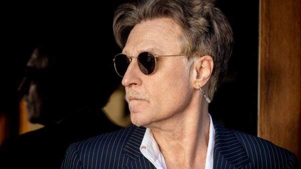 Side profile of a man in a pinstripe suit and sunglasses