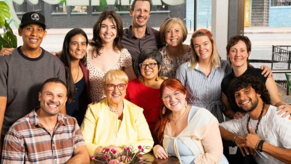Lidia sits smiling with volunteers huddled around her