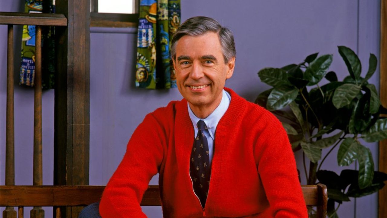 Mister Rogers wearing a red sweater and black tie