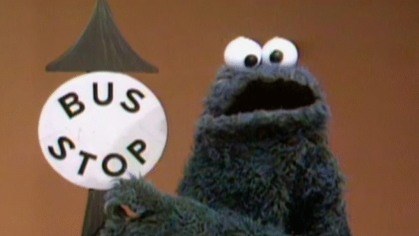 cookie monster holding a bus stop sign