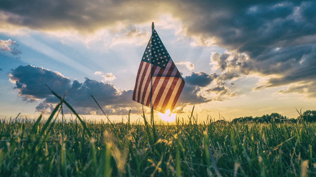American flag placed in a field with the sun setting in the background