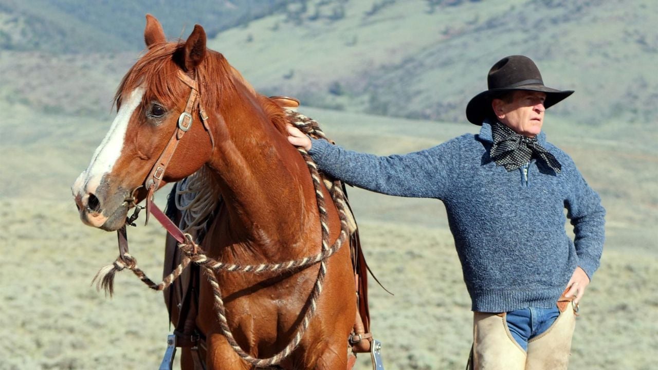 A man stands by his horse in a valley