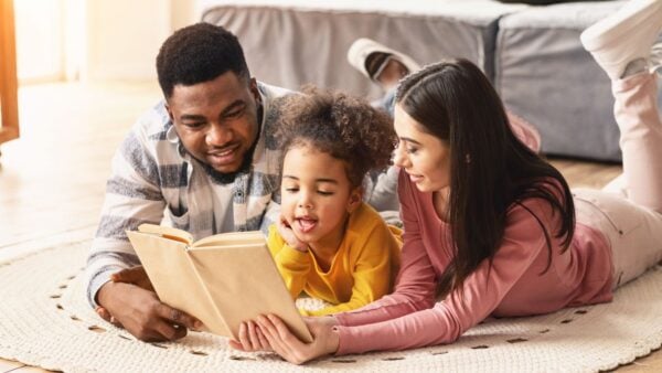 Two parents reading a book with a child