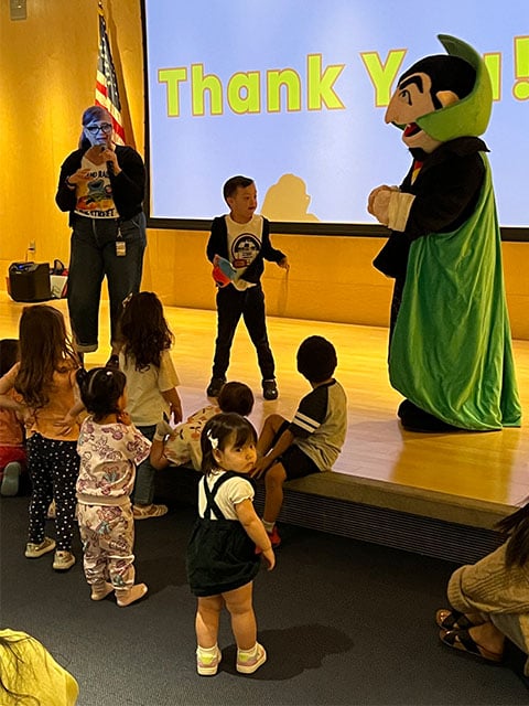 A group of children on stage with a colorful mascot