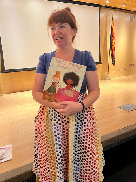 A woman in a vibrant dress holds a book