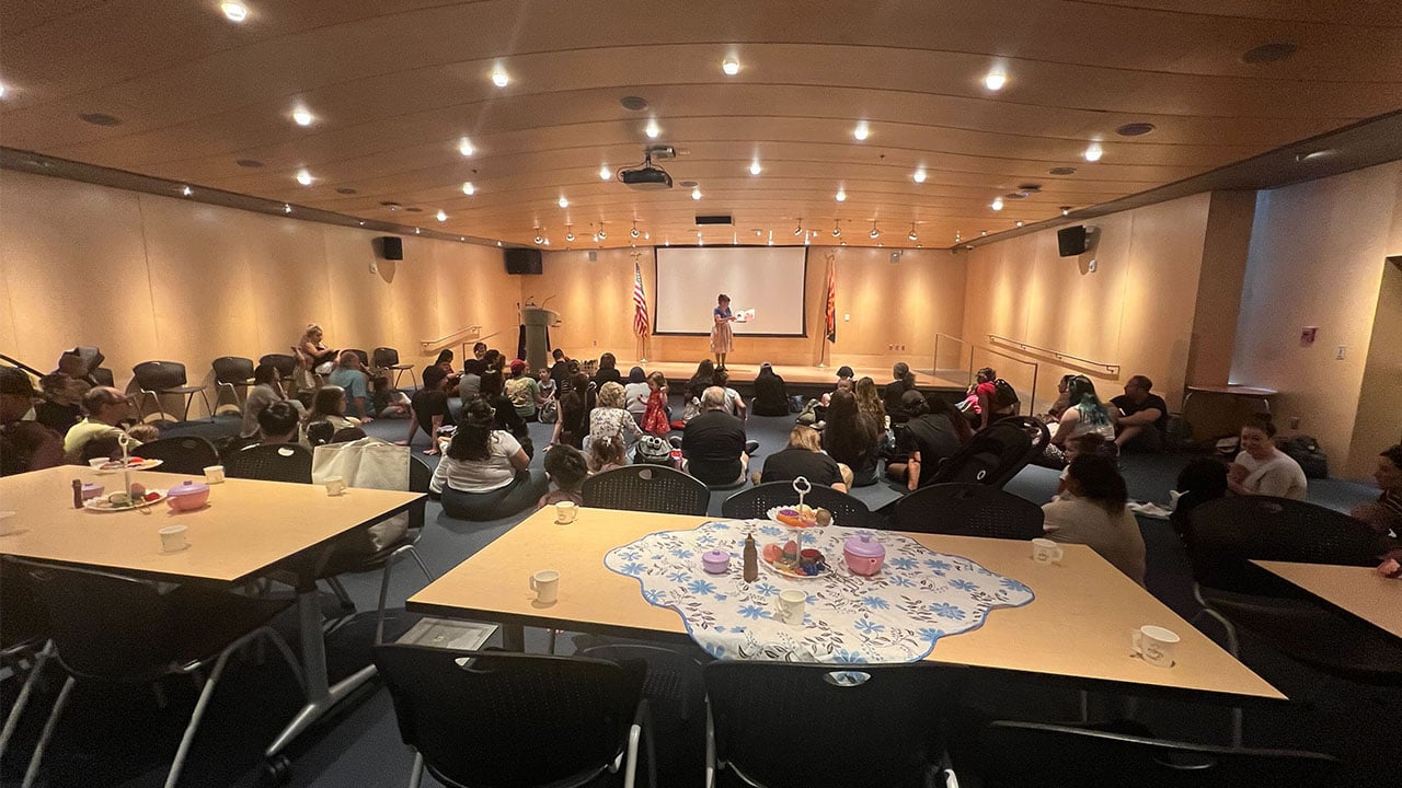A spacious room filled with tables and chairs, occupied by people engaged in conversation and activities.