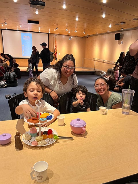 Kids gathered around a table, smiling and sharing a cupcake together.