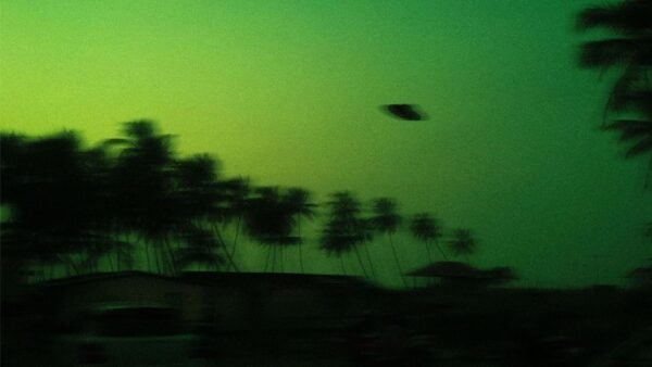 A UFO flying over a landscape of palm trees