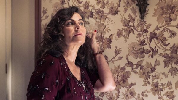 A woman using a cup to listen through a wall