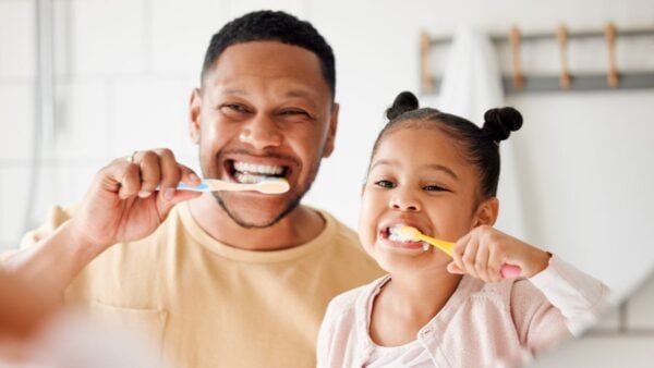 A father and child brushing their teeth together