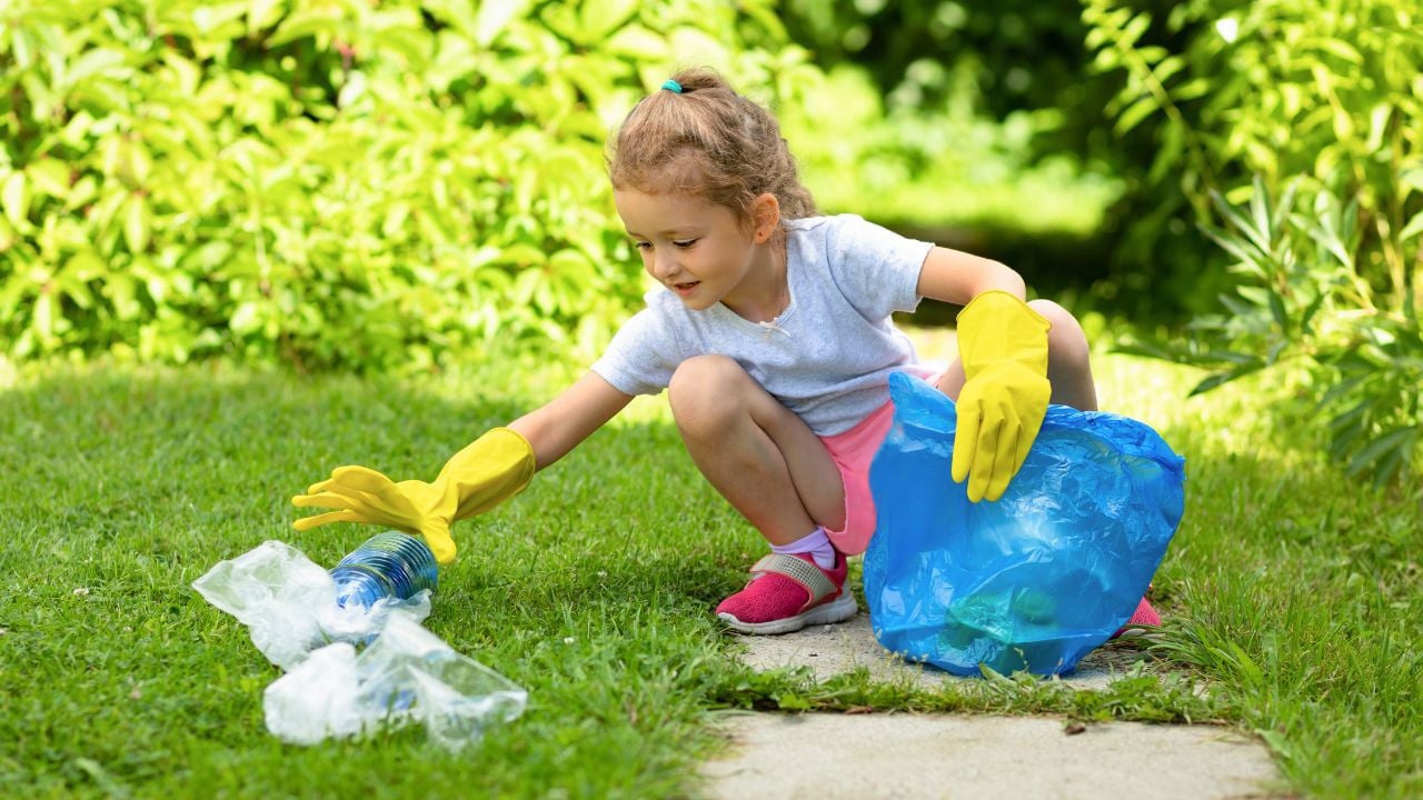A young child picking up trash from the ground
