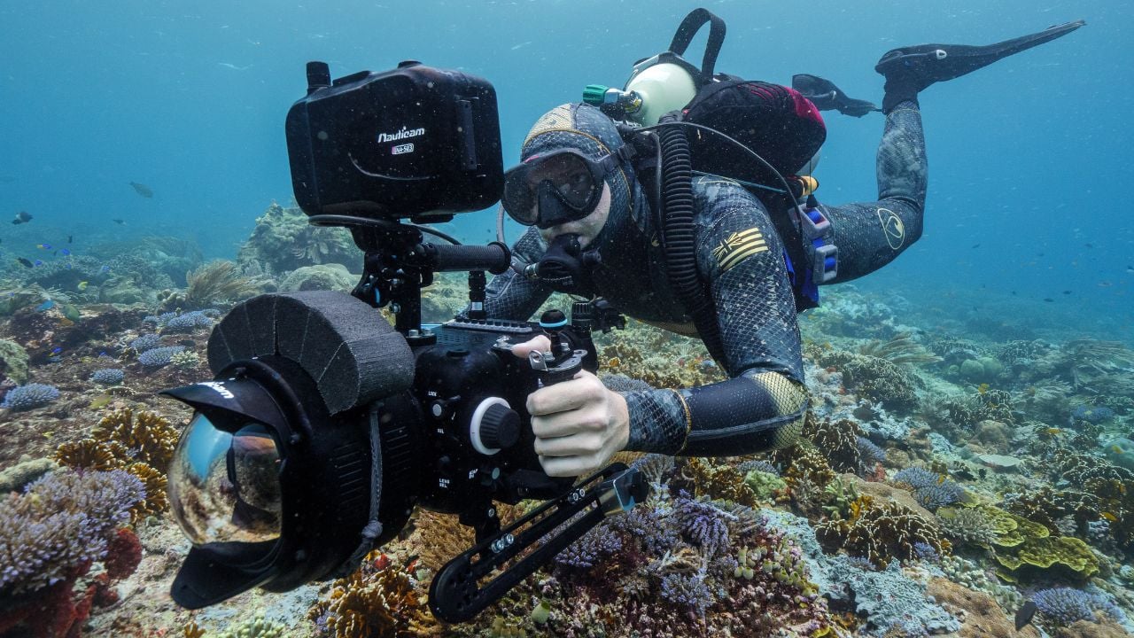 A man scuba diving, capturing the scenery with a camera
