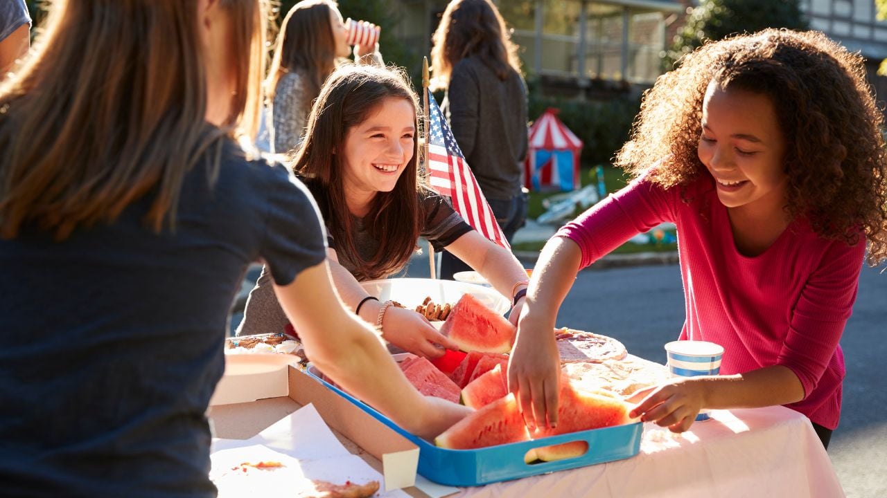 Kids smiling and passing out watermelon at an event