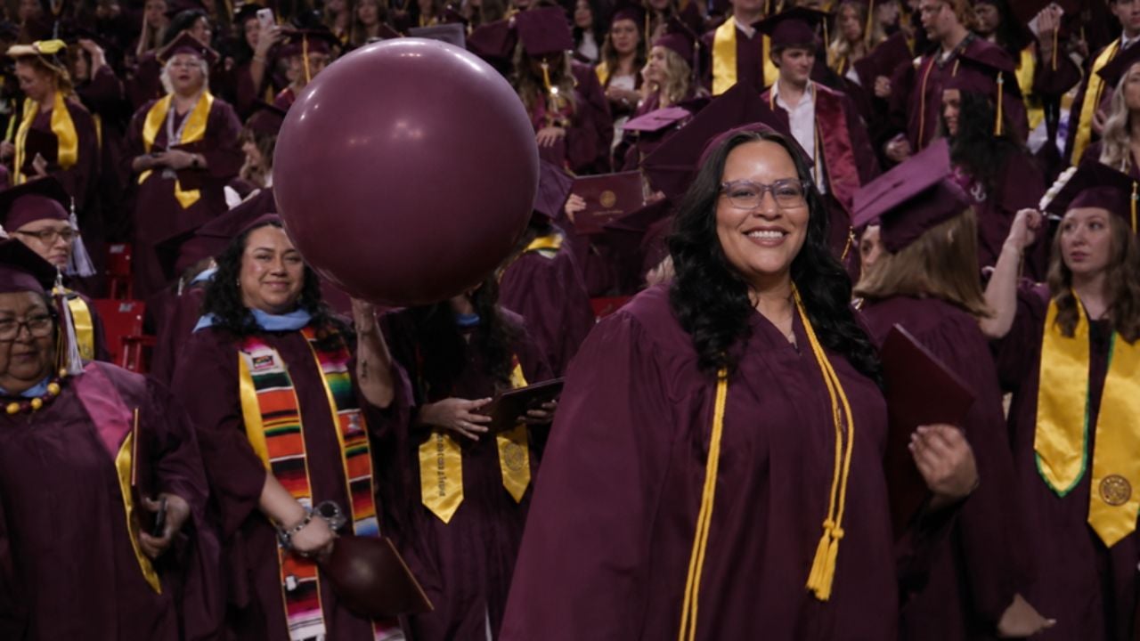 Angela Paschal in a cap and gown, holding her diploma