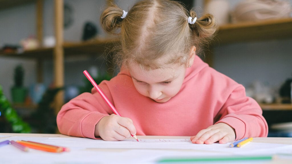 A girl sits at a table coloring