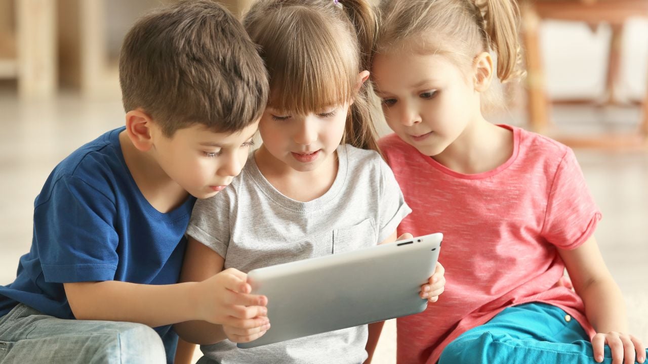 Three young children playing on a tablet