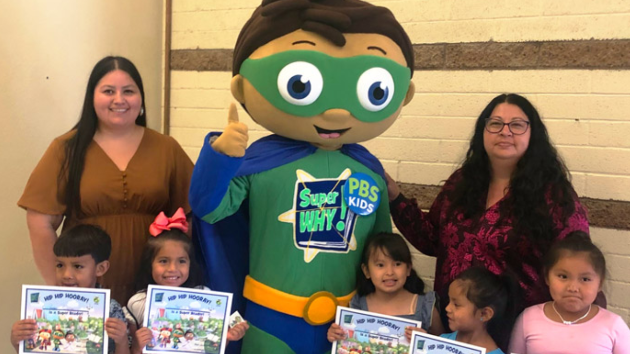 Super Why poses with a group of children