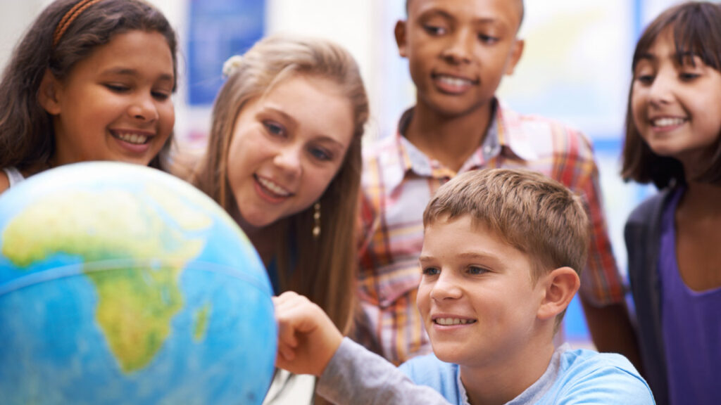 Elementary aged children look at Latin America on a globe