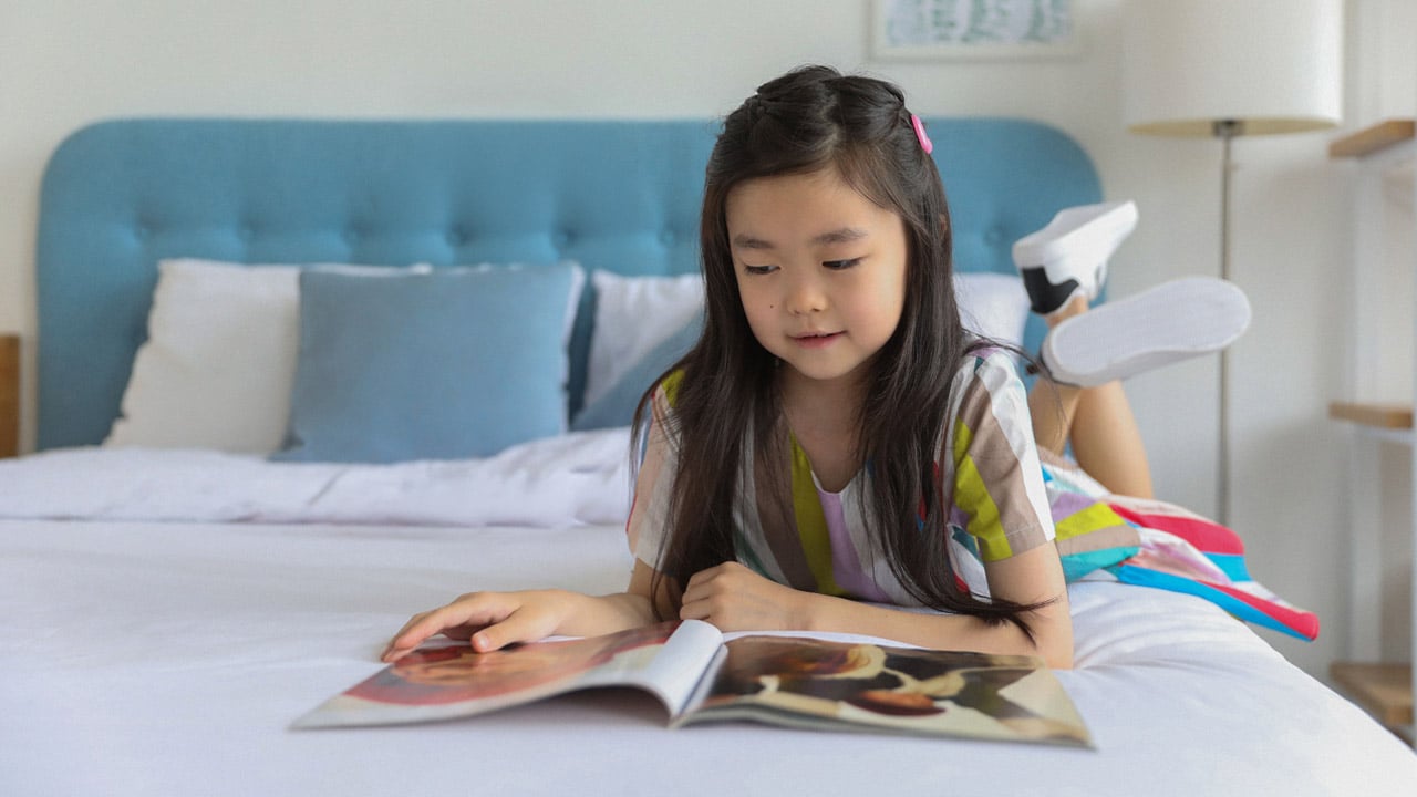 A young girl reads a magazine
