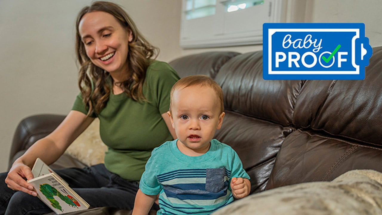 A mother reads a book to her toddler while sitting on a couch