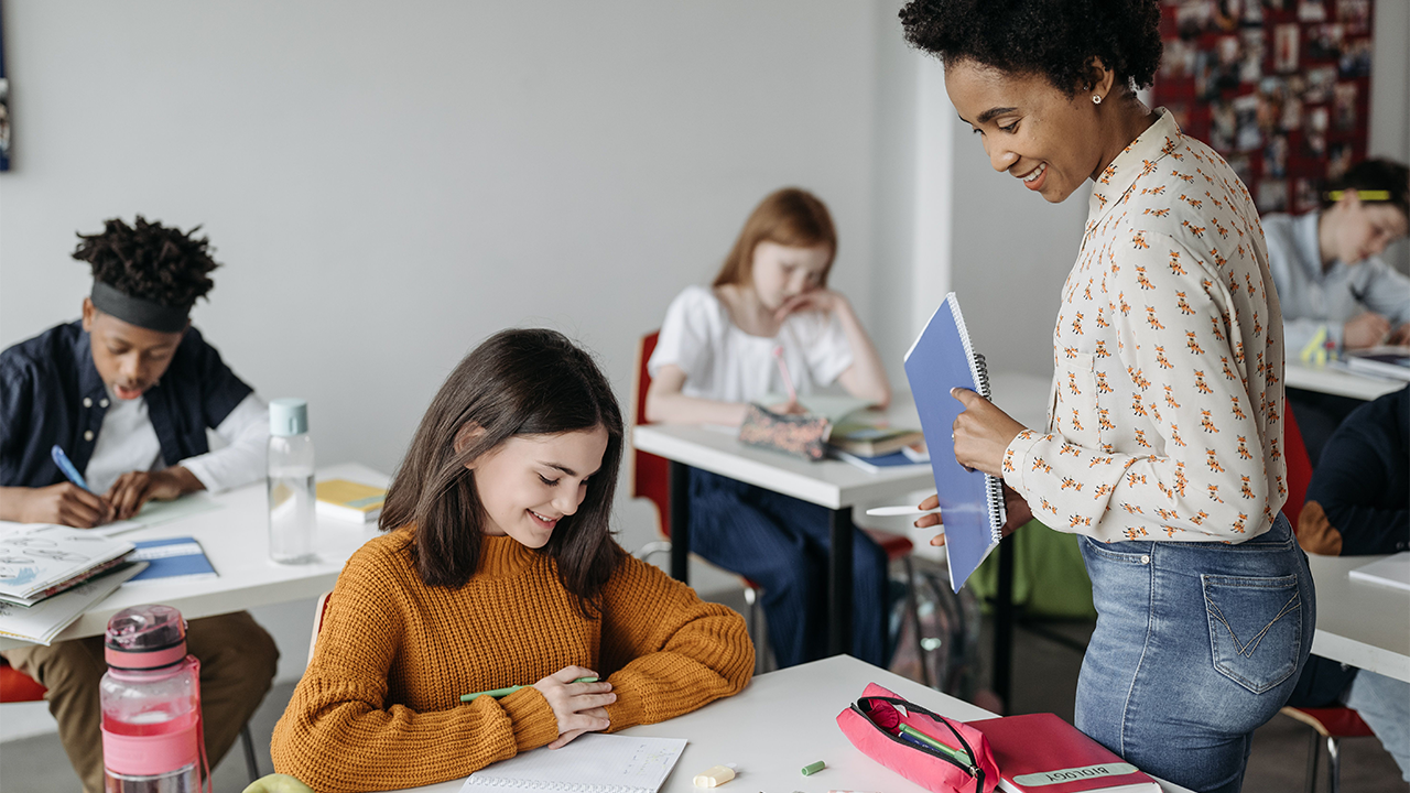 Teacher looking over students' work in classroom